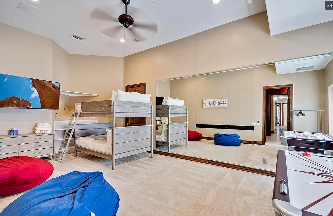 Spacious vacation rental bunk room with double bunk beds, bean bag chairs, air hockey table and mirrored wall
